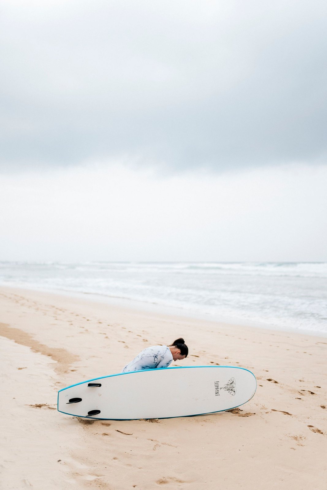 Surfer resting beside her board on the beach at Ahangama