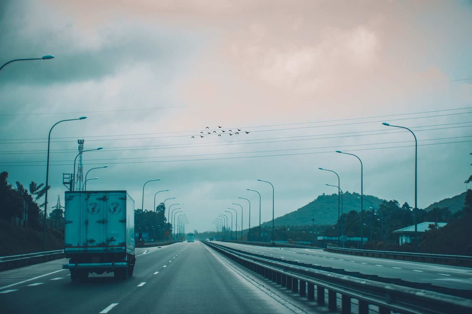 Truck driving along a Sri Lankan expressway towards green hills