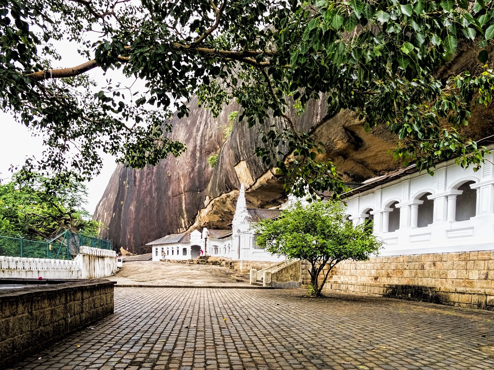 Whitewashed entrance of the Dambulla cave temple beneath the rock overhang