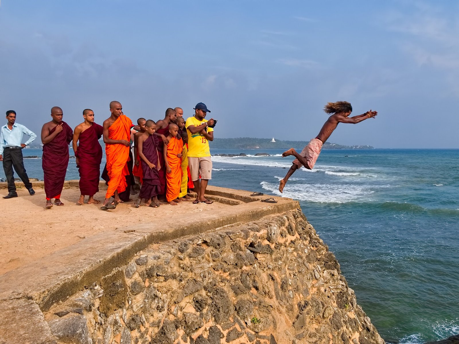 Monks watch a local diver leap from Flag Rock bastion at Galle Fort