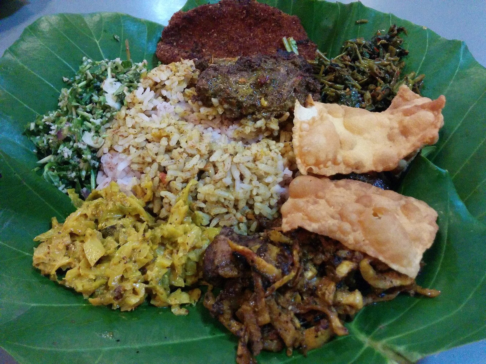 Rice and curry with several sides served on a banana leaf