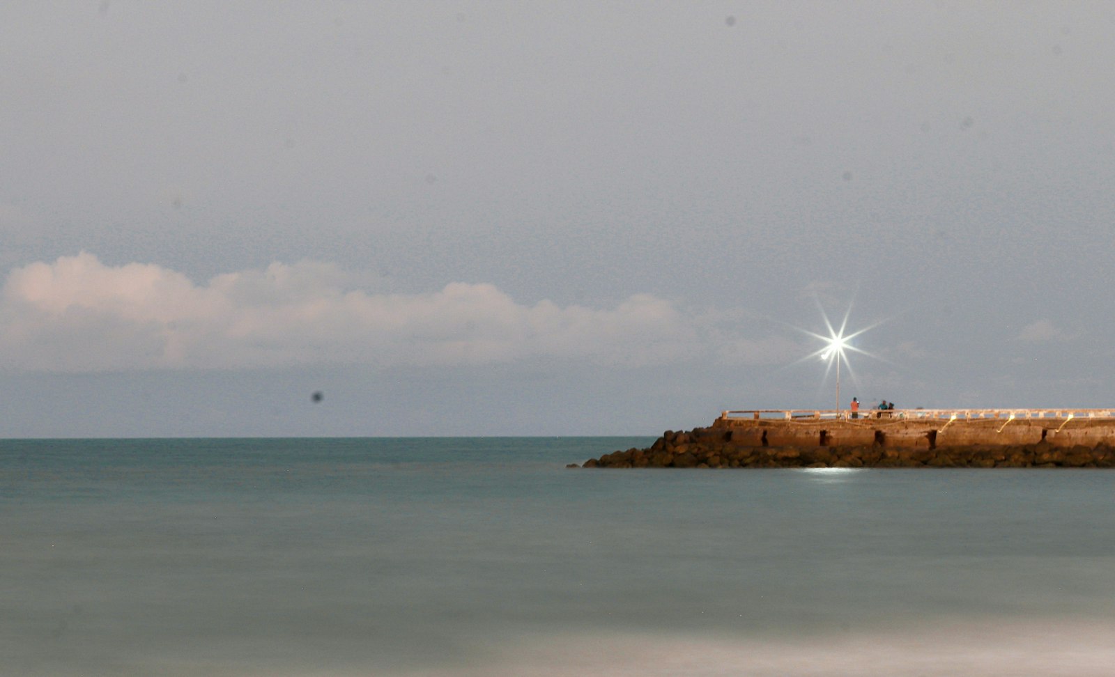 Lighthouse on a stone pier by the ocean